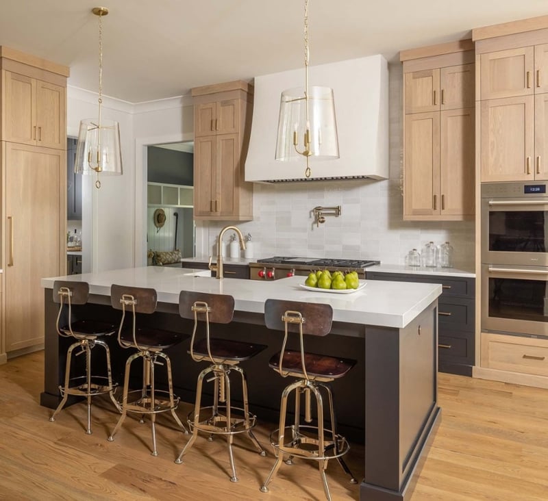 Custom kitchen with light wood cabinets, dark gray island, and quartz countertops. 
